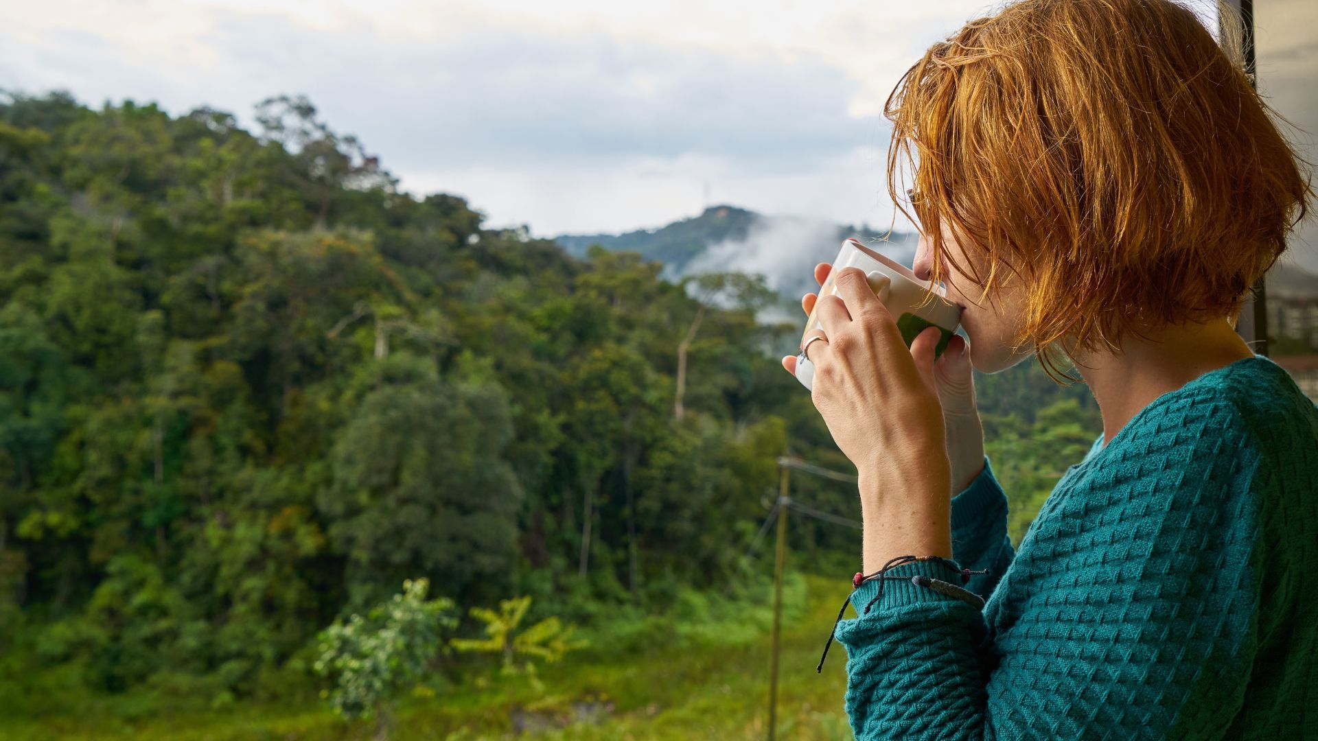 A woman looks out of her window to the wilderness.